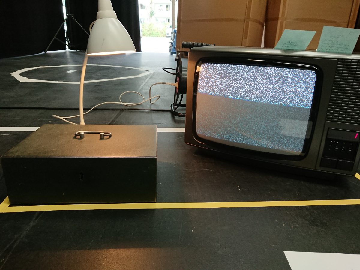 a photo of a studio space: on the floor a tv, a metal box and a lamp