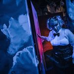 eine junge frau im steampunk kostüm in einer dunklen höhle