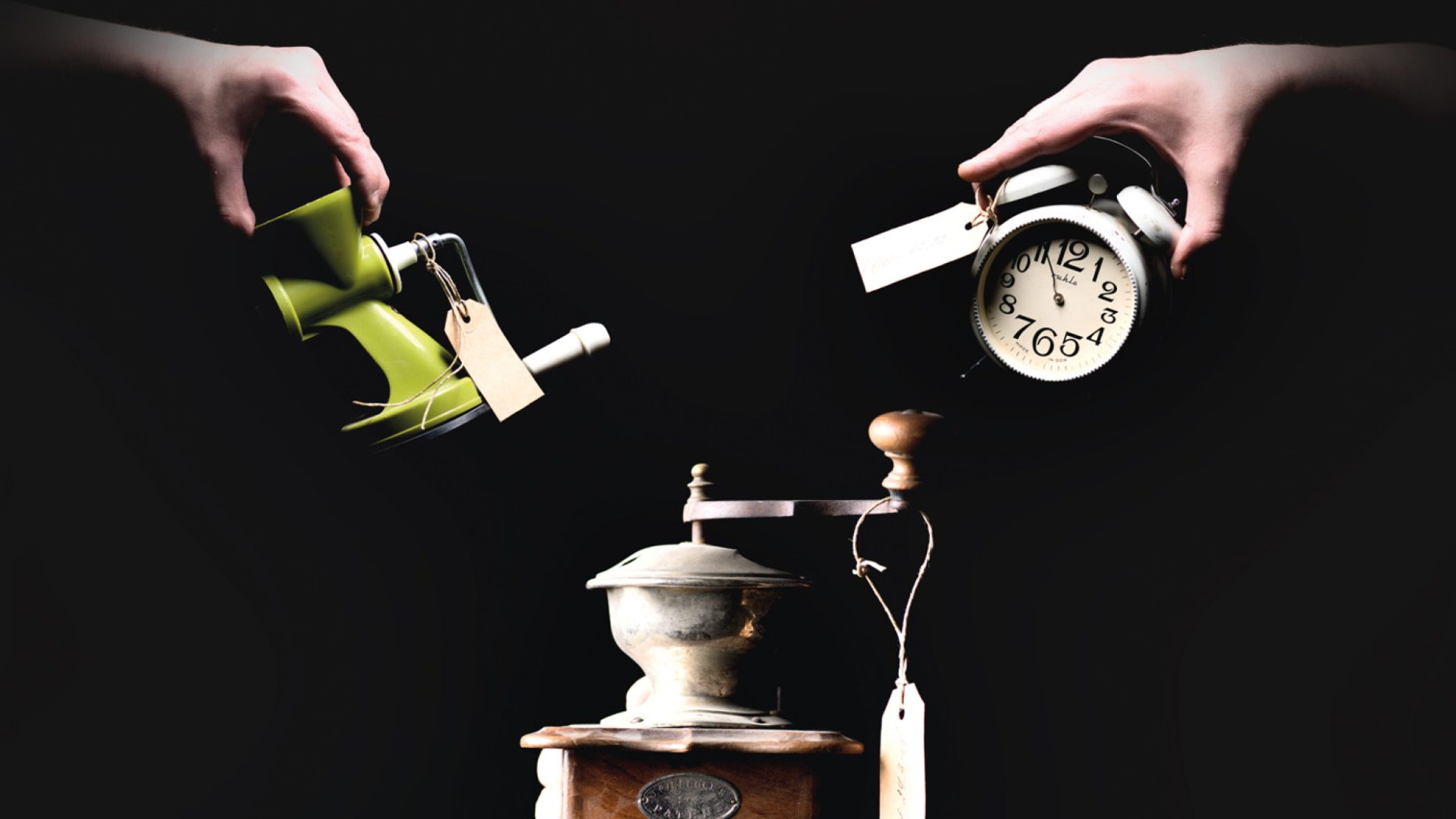 the poster of the show. three old objects are seen: a coffee grinder, an alarm clock and a mincer. each has a tag on it. the latter two are held by hands