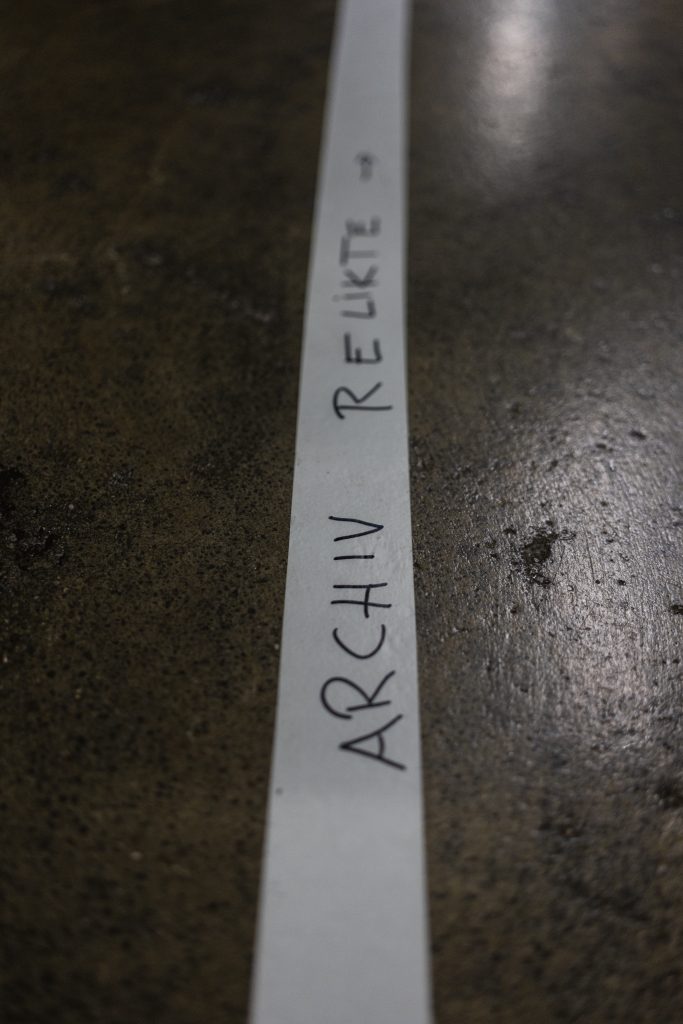 a tape on the floor that reads "archive relics" and an arrow pointing into one direction